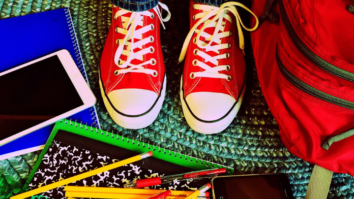 Red tennis shoes surrounded by school supplies