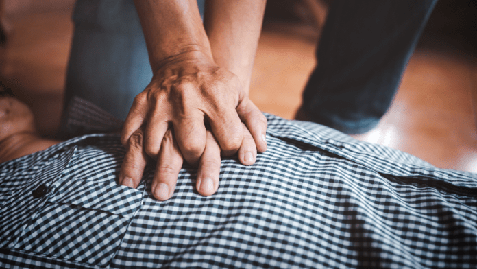 Man chest on ground with hand doing chest compressions