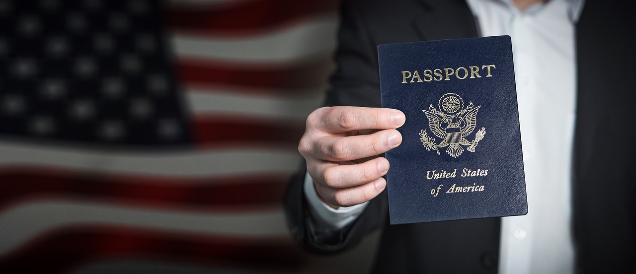 Image of Man holding passport in front of American flag